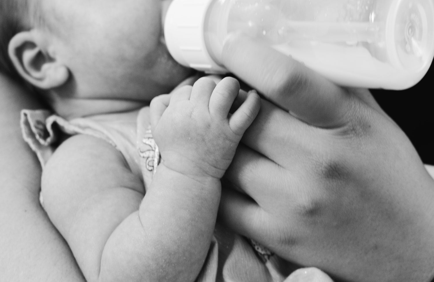 Black and white image of baby being bottle fed